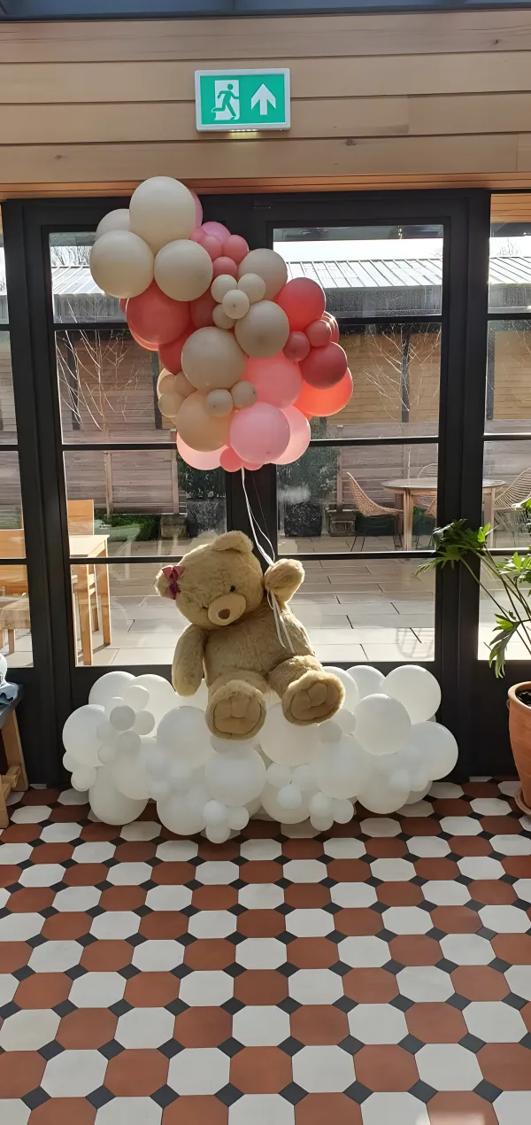 Teddy bear balloon sculpture floating with a bunch of balloons on a cloud base